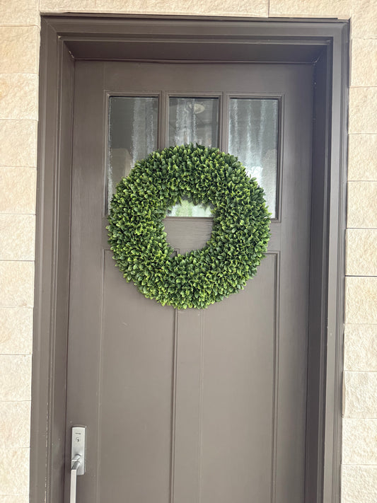 Boxwood wreath on a gray door with beige wall background