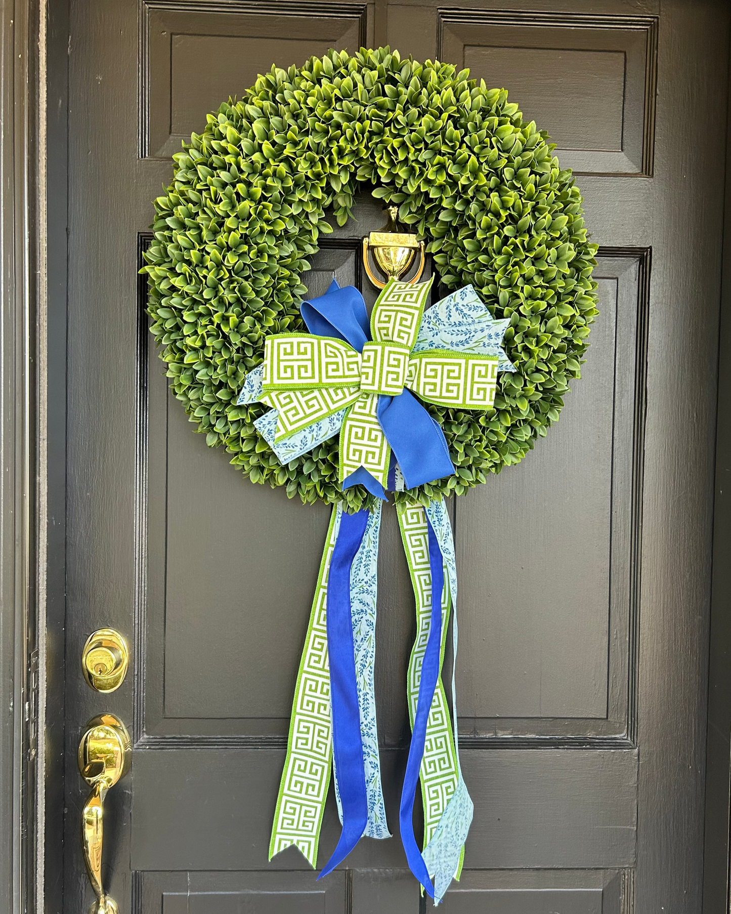 Green wreath with blue and green ribbons on a dark brown door